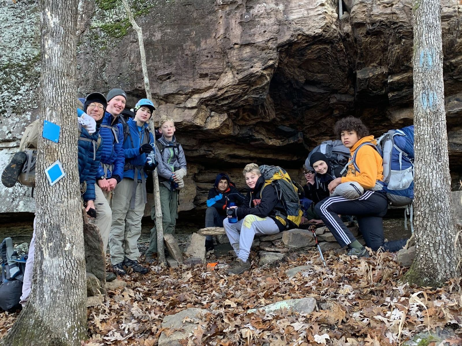 Backpacking crew resting beneath an Ozark rock shelter