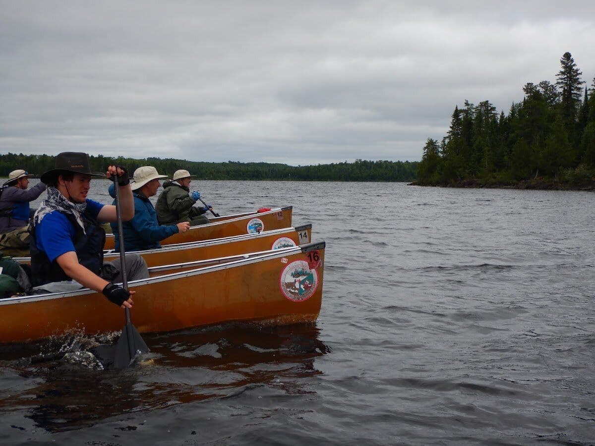 Canoe crew paddling across calm wilderness water
