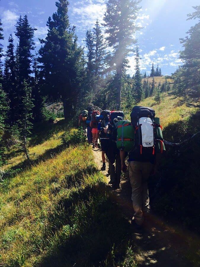 Backpacking crew moving through a forested mountain trail